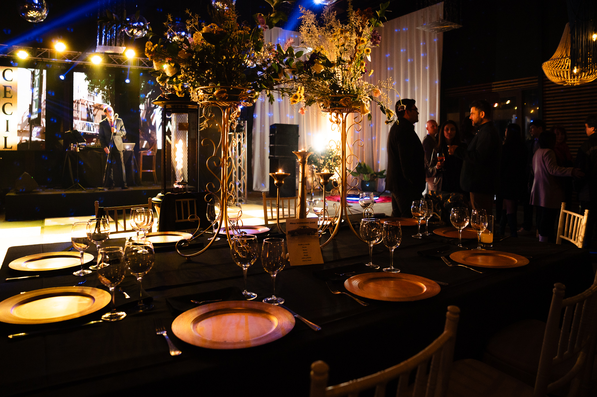 Mesa dispuesta con centros de flores, escenario y show de fondo