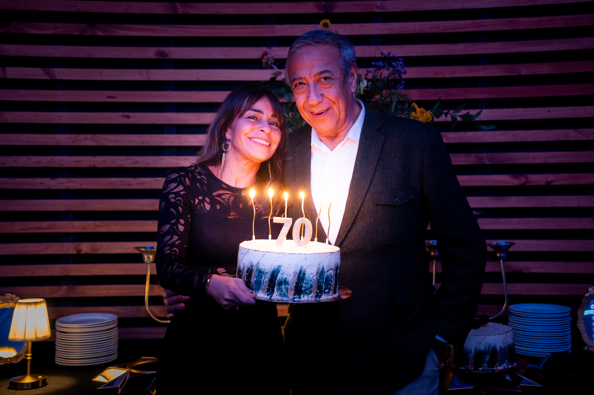 Pareja sosteniendo la torta con las velas número 70